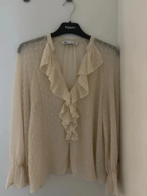 Beige volangblus från Zara - Söt beige blus från Zara med volangdetaljer längs ringningen och framtill. Använder aldrig ❤️