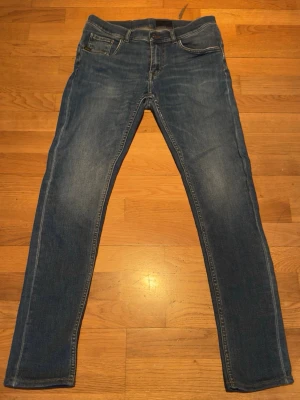 Tiger of Sweden jeans w30 l32 - Snygga blå jeans från Tiger of Sweden med klassisk femficksmodell och diskreta slitningar. Jeansen har raka ben och är tillverkade i mjukt denimtyg som ger en skön passform. Perfekta för dig som gillar stilrena och tidlösa jeans.