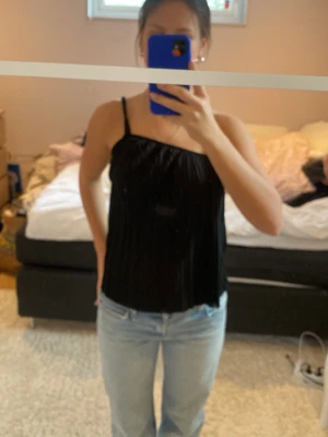 Svart linnetopp med smala axelband - Säljer en svart linnetopp med smala axelband och rak passform. Perfekt för dig som gillar en enkel och stilren look. Toppen är ärmlös och har en luftig känsla, passar bra till jeans eller kjol.