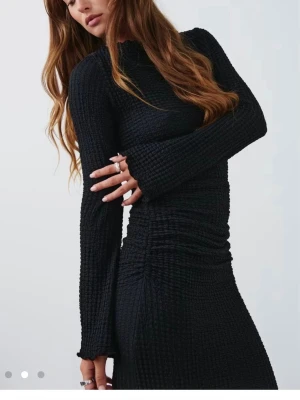 Svart långärmad klänning - Säljer en svart långklänning med ribbad struktur och långärmad design. Klänningen har en kroppsnära passform och är tillverkad i ett stickat material som ger en snygg siluett. Perfekt för dig som gillar stilrena och trendiga plagg.