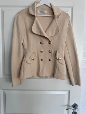 Beige kavaj från Diana Couture - Stilren beige kavaj med dubbelknäppning och sex guldknappar framtill. 
