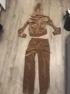 Brunt velourset från Juicy Couture - Säljer mitt bruna juicy sätt där tröjan är i stl M och byxorna i stl XS, jätte fint skick inga defekter. Skulle man vilja köpa separat är de bara att skriva så kommer vi överens om en summa för ena plagget bara 🥰