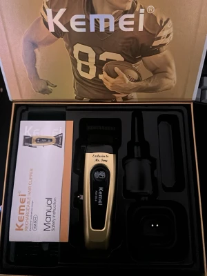 Kemei uppladdningsbar hårtrimmer - Kemei uppladdningsbar hårtrimmer modell KM-90-4 i svart och guld. Trimmern har DLC-blad med självslipande precision och levereras med laddkabel, borste och manual. Perfekt för att fixa frisyren hemma med proffsiga resultat.