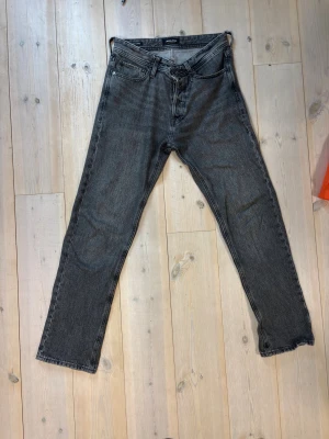 Gråa raka jeans - Säljer ett par gråa raka jeans med klassisk femficksdesign och normal midja. Jeansen har en enkel look utan slitningar och är tillverkade i ett robust denimtyg. Kan tänka mig gå ner i pris vid snabb affär och tveka inte på att höra av dig vid funderingar!