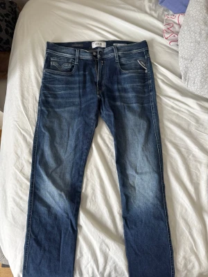 Blå Slim Replay jeans  - Säljer ett par snygga blå jeans från Replay med raka ben och klassisk femficksmodell. Tillverkade i denim med detaljerade sömmar och Replay-lapp bak i midjan. 