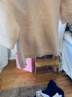 Beige stickad t-shirt med kort ärm - Säljer en beige stickad t-shirt med korta ärmar och rund hals. Tröjan har ribbade muddar vid ärmslut och nederkant, vilket ger en clean och stilren look. Perfekt för lager på lager och enkel att matcha med olika outfits.