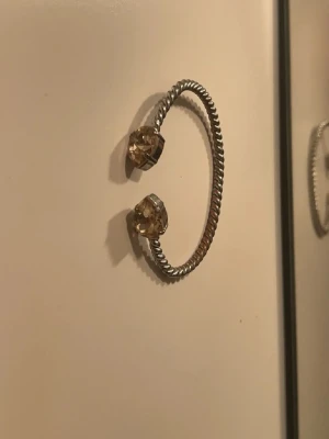 Silvrigt armband med stenar  - Snyggt armband i silverfärgad metall med tvinnad design. Öppningsbar modell med två stora, klara pärlor i varje ände som ger en cool och trendig look. Perfekt accessoar för att lyfta din outfit.