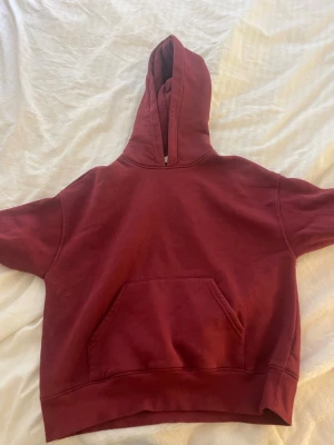 Vinröd hoodie med magficka - En enkel och snygg vinröd hoodie från Ginatricot med stor magficka och huva. Hoodien har ribbade muddar vid ärmslut och nederkant. Perfekt för chill dagar och passar till det mesta. Materialet känns mjukt och bekvämt, troligen bomull eller bomullsblandning.