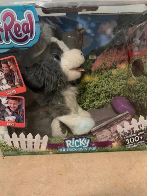 Interaktiv plyschhund Ricky - Säljer en interaktiv plyschhund från FurReal, modellen Ricky The Trick-Lovin' Pup. Hunden är grå och vit med blå ögon och rosa tunga. Den kan utföra tricks och reagerar med över 100 ljud- och rörelsekombinationer. Perfekt för dig som gillar roliga och smarta leksaker.