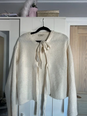 Vit stickad kofta från Gina Tricot - Säljer en krämvit stickad kofta från Gina Tricot med knytband framtill. Använd fåtal gånger då jag inte trivs i den