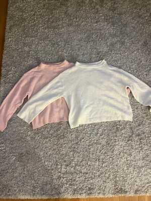 Två stickade tröjor i pastell - Två stickade tröjor i mjuka pastellfärger, en i ljusrosa och en i vitt. Båda har lång ärm, rak passform och ribbstickade muddar vid ärmslut och nederkant. Perfekta för lager-på-lager och chill dagar. 100kr för båda, 50kr styck