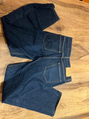 Mörkblå jeans från GANT - Snygga mörkblå jeans från GANT med klassisk femficksdesign och raka ben. Jeansen har kontrastsömmar och är tillverkade i slitstark denim. Perfekta för dig som gillar en tidlös och clean look.