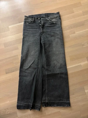 Hope Skid Jeans - Säljer ett par svarta wide leg jeans med hög midja och knäppning fram. Jeansen har klassiska fem fickor och slitna detaljer vid benslut. Materialet är kraftig denim som ger en cool vintagekänsla. Perfekta för dig som gillar avslappnad och trendig stil.