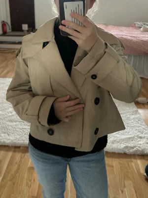 Kort beige trenchcoat från Zara - Populär trenchcoat från Zara ☺️har en luva som man kan välja om man vill ha på eller inte genom en dragkedja 😊