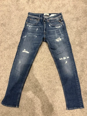 Replay W29 - Ett par blå replay Willbi med lite schysstare slitningar. Storlek 29/30