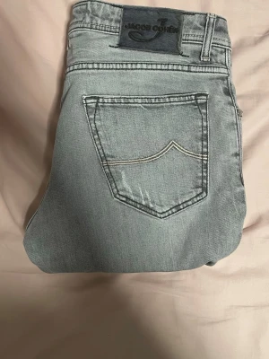 Ljusblå jeans från Jacob Cohen - Snygga ljusblå jeans från Jacob Cohen med klassisk femficksdesign och kontrastsömmar på bakfickan. Jeansen har en rak passform och är tillverkade i mjukt denimtyg. Perfekta för en avslappnad och trendig look.