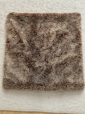 Två Bruna fluffiga kuddfodraler i fuskpäls - Säljer ett fyrkantigt kuddfodral i mjuk och fluffig fuskpäls med bruna och beige toner. Baksidan är slät och har en varm brun färg med öppning för kudde. Perfekt för att ge soffan eller sängen en mysig känsla.