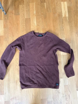 Brun stickad tröja från Jack & Jones - Mysig brun stickad tröja från Jack & Jones med rund halsringning och diskret struktur i materialet. Tröjan har långa ärmar och en enkel, stilren design som passar perfekt till jeans eller chinos.