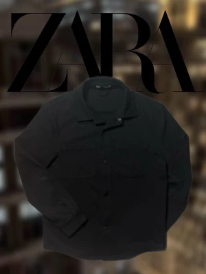 Zara Overshirt - En svart overshirt från Zara med långa ärmar och krage. Modellen i bild 2 är ca 187cm och 80kg. Den har använts ett par tillfällen men är fortfarande i fint skick! Saknar dock översta knappen. Om du vill diskutera pris eller har andra funderingar är det bara att höra av sig!