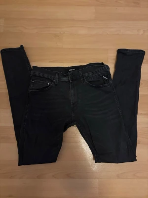 Svarta slim fit jeans från Replay - Svarta slim fit jeans från Replay med klassisk femficksdesign och diskreta slitningar. Jeansen har smal passform och normal midja, perfekt för en stilren och modern look. Materialet är stretchigt för extra komfort. Kan diskutera pris