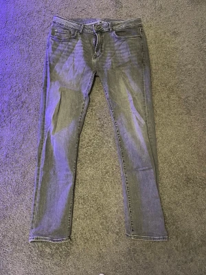 Grå slim fit jeans från Dressmann - Snygga grå slim fit jeans från Dressmann med klassisk femficksdesign och dragkedjegylf. Jeansen har en modern passform som sitter tajt längs benen och är perfekta för en stilren.