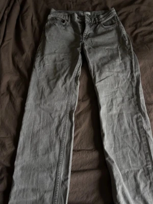 Gråa jeans från gina - Säljer ett par grå jeans med klassisk femficksdesign. Jeansen har bälteshällor och knappgylf. Materialet är denim och färgen är en snygg tvättad grå som passar till det mesta. Perfekta för en avslappnad och stilren look. Mer baggy i passformen. Säljer då de inte längre kommer till användning.🤩