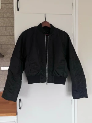 Y2K boxig clean bomberjacka Gina Tricot stl S - nyskick - Boxig bomberjacka från Gina Tricot, storlek S. Knappt använd och i superfint skick!  Perfekt för en clean Y2K-look – tänk low waist jeans, babytee och chunky sneakers. Den ger verkligen den där lite oversized, coola 00-talskänslan. Fler bilder finns om så önskas!