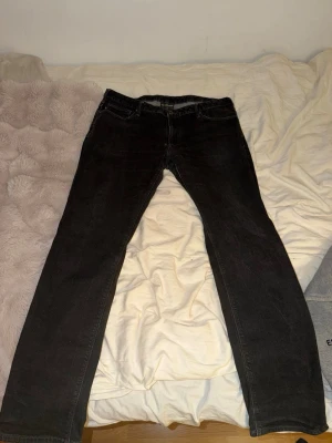 Svarta jeans från Emporio Armani - Säljer ett par svarta jeans från Emporio Armani med klassisk femficksdesign och rak passform. Jeansen har en diskret logga på myntfickan och är tillverkade i ett mjukt denimtyg. Perfekta för en stilren och avslappnad look.