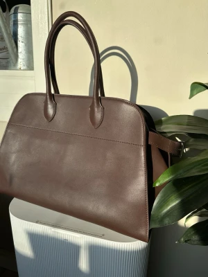 The Row Margaux 15 - Stilren IT väska i 100% äkta mjukt läder, slouchy. Väskan har en minimalistisk design som passar till många olika looks. Perfekt för dig som gillar enkel men elegant stil. Dustbag medföljer. Fantastisk väska som kommer ge dig många komplimanger 🌸