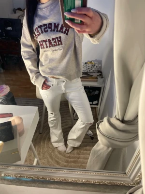 Vita lowrise bootcut jeans  - Säljer ett par vita jeans från Gina Tricot med bootcut och slitningar vid knäna. Jeansen har klassisk femficksmodell, ultra låg midja och är tillverkade i ett mjukt bomullsmaterial. Perfekta för en avslappnad och trendig look.