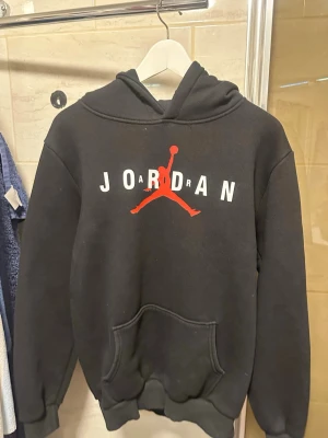 Svart Jordan hoodie  - Säljer en svart hoodie från Jordan med den klassiska Jumpman loggan i rött och vitt tryck på bröstet. 