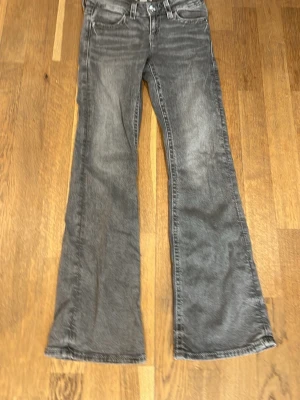 Grå bootcut jeans - Snygga grå bootcut jeans med broderad bakficka och dekorativ knapp. Jeansen har klassisk femficksdesign och utsvängda ben. Storlek 152