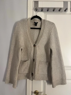 Beige stickad kofta  - Supersöt beige stickad kofta från Lindex. Tre knappar och fickor framtill. I mycket bra skick! 