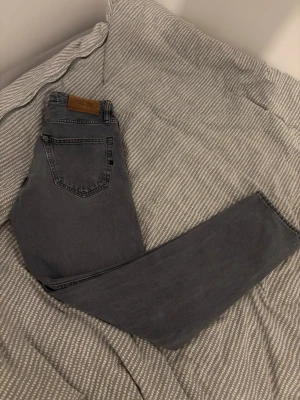 Grå raka jeans från Jack & Jones - Säljer ett par grå jeans från Jack & Jones med klassisk femficksmodell och raka ben. Jeansen har en snygg tvättad look och används ett  fåtal gånger. Skicket är som nytt. 