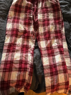 Röd-rutiga pyjamasbyxor M - Mysiga pyjamasbyxor i röd, vit och rosa rutigt mönster. Tillverkade i mjuk bomull, säljes pga att dom var för korta i benen för mig.