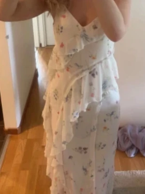  Points vit blommig omlottklänning -  Söt långklänning från Gina tricot i vit med blommigt m declared nster i pastellfärger. Klänningen har omlottmodell med volangdetal cinema jer och smala axel WP band. Perfekt för varma dagar och somriga tillfällen som skolavslutning eller midsommar.🌸💕nypris: 600. Använd en gång, säljs inte längre.