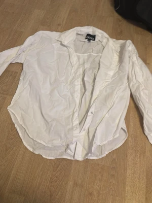 Vit klassisk skjorta från Pieces - Säljer en vit skjorta från Pieces med klassisk krage och knappar framtill. Skjortan har lång ärm och är tillverkad i ett tunt bomullstyg som känns lätt och skönt. Perfekt att styla till jeans eller kjol för en clean look.