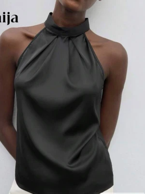 Svart halterneck topp med knyt vid ryggen - Snygg svart topp med krage och knytband i nacken. Toppens material har en lätt glans och är mjukt och bra . Perfekt fest topp. Har aldrig använt heller. 