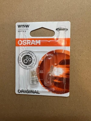 OSRAM W5W 12V 5W glödlampor - Två genomskinliga reservdelslampor från OSRAM, modell W5W 12V 5W. Lamporna är små och cylinderformade, tillverkade i glas och metall. Perfekta som ersättningslampor till bilens belysning. Förpackningen är vit och orange med tydlig sopartslogga.