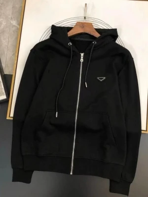 Svart zip hoodie med logga - Snygg svart hoodie med dragkedja från Prada. Hoodien har huva med dragsko, ribbade muddar och fickor framtill. Liten metalllogga på bröstet ger en exklusiv touch. Perfekt för en clean och stilren look.