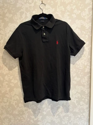 Svart Ralph Lauren pike - Säljer en snygg Ralph Lauren piké i storlek m custom fit😮‍💨Piken har blivit lite skrynklig men det är inget som förstör helhets intrycket🤗 Den är perfekt nu när det börjar bli lite varmare ute🏖️Hör av er om ni har någon fråga👍