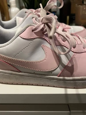 Nike rosa och vita sneakers - Ett par Nike rosa och vita air forces för tjejer pris kan diskuteras.