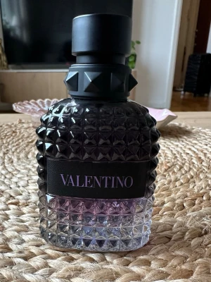 valentino purple melancholia  - Den är använd flera gånger men den innehåller 45 ml/50 ml kvar. Snygg parfymflaska från Valentino med nitar på halsen och ett mönstrat glas i svart och lila nyans. Flaskan rymmer 50 ml och har en lyxig, modern design med tydlig logga på framsidan. Perfekt för dig som gillar exklusiva dofter och stilren look.