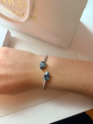 Armband Caroline Svedbom - Snyggt silvrigt armband från Caroline Svedbom i färgen ”Ice Blue”. Säljer då jag bytt till guld:)                                 Perfekt accessoar för att lyfta din outfit med lite extra bling. Skicket är mycket bra, inga skador😊                                                            Nypris 900 kr💗Säljer för 650 kr men pris går alltid att diskuteras💗Skriv gärna för fler bilder eller funderingar!
