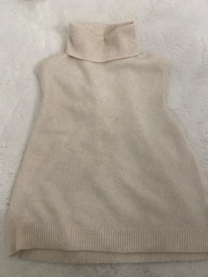 Stickad tröja - Mjuk och stilren beige stickad tröja med hög polokrage. Tröjan  har en rak passform och ribbade detaljer vid krage och nederkant. 