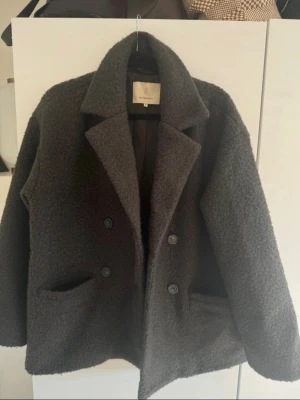 Mörkgrå teddyjacka - Säljer en mörkgrå teddyjacka från Weekday Tjock sopig textur, dubbelknäppt rotating sopiga knappar och två stora fickor framtill. Aldrig använd ☀️