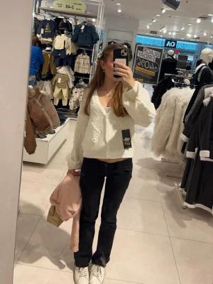 Vit stickad kofta med mönster - Mysig vit stickad kofta från C&A med dekorativa mönster och knappar framtill. Koftan har v-ringning, långa ärmar och ribbade muddar. Perfekt för lager-på-lager och en trendig look.