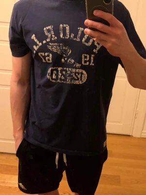 Mörkblå Polo Ralph Lauren t-shirt - Otroligt sällsynt och snygg mörkblå t-shirt från Polo Ralph Lauren med vit logga och text framtill. Klassisk passform och rund halsringning. Perfekt till jeans eller shorts för en avslappnad look. Storlek M. Nypris ca 1600 kr. Pris kan alltid diskuteras✅.