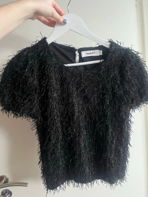 Svart ”fluffig” glitter topp från Kappahl - Cool svart topp från Kappahl med fluffig, glittrig textur och korta ärmar. Perfekt för dig som vill sticka ut med en unik och trendig look!🥰