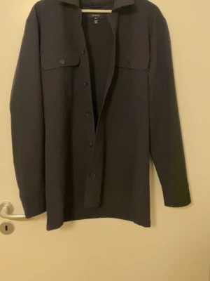 Svart overshirt från Matinique  - Stilren svart overshirt från matinique med klassisk krage, knäppning framtill och två bröstfickor med lock. Overshirten har raka ärmar och en avslappnad passform. Perfekt att bära som lager över en t-shirt. Materialet känns mjukt och lite tjockare. Köpt för 700kr säljer för 450 pris kan ej diskuteras